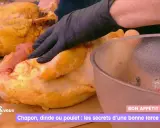 Main d'un cuisinier en gant noir préparant une farce poulet avec abats. Un chapon doré est à côté.