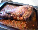 Gigot de sanglier rôti 7h, baignant dans son jus avec des légumes coupés. Un plat savoureux prêt à être dégusté.