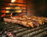 Bifteck grillé sur le feu, prêt à être servi avec une sauce piquante.