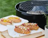 Délicieux hot dogs prêts pour un barbecue, avec des garnitures fraîches et un pain aux graines.