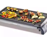 Brochettes de noix de Saint-Jacques et légumes colorés sur une plancha Tefal, prêts à être grillés pour un repas savoureux.