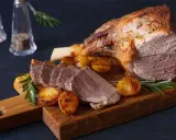 Gigot d'agneau rôti, pommes de terre et romarin sur une planche en bois. Un plat parfait pour la viande pour Pâques.