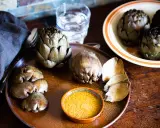 Artichauts prêts à être dégustés, accompagnés d'une sauce savoureuse. Une idée pour une recette artichaut simple et délicieuse.