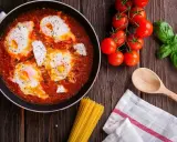 Œufs pochés dans une sauce tomate savoureuse, rappelant la sauce armoricaine, avec des tomates fraîches et du basilic.