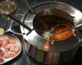 Préparation pour comment faire une fondue bourguignonne : morceaux de viande crue, pain et huile chaude dans le caquelon.