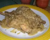Un plat de lapin à la moutarde, crémeux et savoureux, servi sur une assiette blanche bordée de jaune.