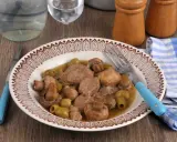 Un délicieux sauté de veau aux olives et champignons, servi dans une assiette décorée, prêt à être dégusté avec une fourchette bleue.
