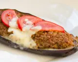 Aubergine farcie à la viande hachée, gratinée au fromage et garnie de rondelles de tomate. Une recette savoureuse et réconfortante.