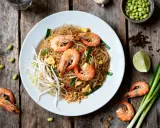 Délicieux Pad Thaï aux crevettes, une recette simple et savoureuse. Nouilles, pousses de soja, œuf, oignons verts et crevettes.