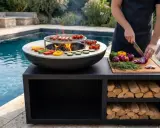 Un homme prépare des légumes pour le barbecue, près d'une piscine. Le culottage de la plancha inox est prêt pour la cuisson.
