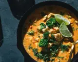 Un plat de poulet et brocolis baignant dans une sauce curry crémeuse, garni de quartiers de citron vert et de persil frais. Un délice !