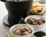 Préparation d'une fondue bourguignonne : viande blanche crue, viande cuite, pain et sauce. Des fourchettes à fondue sont prêtes.