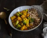 Un bol de riz et un curry de légumes coloré avec du brocoli, de la courge et des pois chiches.
