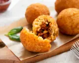 Arancini dorés et croustillants, un délice de la recette arancini, servis avec du basilic frais.