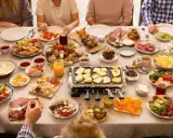 Une table conviviale pour une idée plateau raclette : fromages, charcuteries, légumes et pommes de terre attendent d'être fondus.