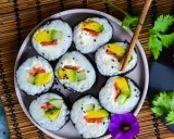 Assiette de makis frais, parfaits pour une recette sushi maison. Avocat, saumon et concombre roulés dans du riz et des algues, parsemés de graines de sésame.