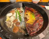 Une fondue chinoise à deux bouillons : un clair avec champignons et légumes, l'autre épicé aux piments.