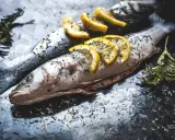 Deux poissons entiers, assaisonnés d'herbes et garnis de rondelles de citron, prêts pour un quel poisson barbecue.
