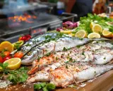 Poissons entiers et filets prêts pour le barbecue, accompagnés de citrons, tomates et herbes fraîches. Un délice en perspective !