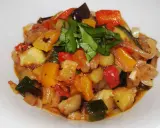 Un plat coloré de ratatouille recette, avec des dés de courgettes, aubergines, poivrons et tomates, garni de basilic frais.