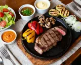 Un steak grillé, poivrons, champignons, courgettes et une sauce pierrade maison savoureuse.