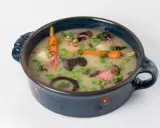 Délicieuse recette végétarienne : un potage crémeux aux carottes, petits pois, pommes de terre et champignons, garni d'oignons rouges et de ciboule.