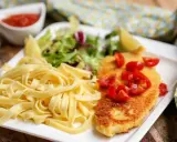 Une assiette de pâtes fraîches, une escalope milanaise dorée garnie de tomates cerises, et une salade verte. Un délice !