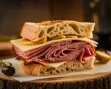 Un généreux sandwich au pastrami, fromage et moutarde, prêt à être dégusté. Une recette simple et savoureuse.