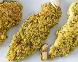 Trois tendres morceaux de poulet pistache, croustillants et dorés, sont présentés sur fond blanc.