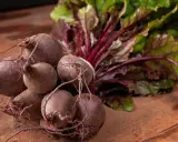 Un bouquet de betteraves fraîches, prêtes pour une délicieuse recette betterave. Leurs feuilles vertes et leurs racines pourpres promettent saveur et couleur.