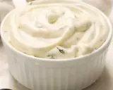 Un bol blanc rempli de sauce césar crémeuse, parsemée d'herbes vertes. Parfait pour accompagner une salade.