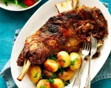 Épaule d'agneau rôtie, servie avec des pommes de terre et du persil. Le temps de cuisson de l'épaule d'agneau au barbecue Weber est parfait pour cette viande tendre.