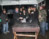Un groupe d'amis profite d'un barbecue sous la pluie, sous un abri. L'ambiance est conviviale malgré les gouttes.