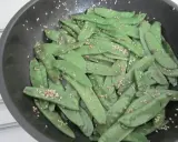 Pois gourmand croquants saupoudrés de graines de sésame dans une poêle.