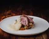 Tranches de gigot d'agneau rosées, nappées d'une sauce chasseur onctueuse, servies sur des pommes de terre rôties. Un délice pour les gourmands.