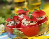 Tomates farcies froides aux légumes, garnies de persil frais, présentées dans un bol en verre. Un délice estival.