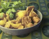 Un bol de colombo de porc, plat épicé aux morceaux de viande et de légumes, garni de coriandre fraîche.