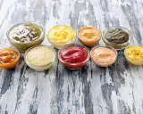 Neuf coupelles de sauces variées, dont le ketchup, la moutarde et des sauces vertes et orangées. Ces sauces sont parmi les 10 sauces les plus utilisées.