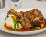 Une souris d'agneau braisée, servie avec une purée onctueuse, des haricots verts croquants et des dés de carottes, le tout nappé d'une sauce savoureuse.