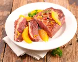 Magret de canard tranché, garni d'orange et de romarin, prêt à être dégusté. Une excellente recette plancha pour un repas savoureux.