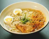 Un bol de ramen poulet avec nouilles, œuf dur, poulet grillé, julienne de carottes et oignons verts. Une recette réconfortante.