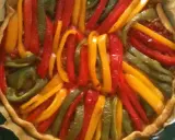 Tarte aux poivrons colorés, un délice visuel et gustatif. Les lanières de poivrons rouges, jaunes et verts forment un motif rayonnant sur la pâte dorée.