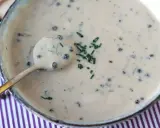 Une cuillère dorée plonge dans une onctueuse sauce au poivre, garnie de ciboulette fraîche.
