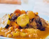 Un plat généreux de couscous algérien, garni de légumes tendres, de pois chiches et de morceaux de viande savoureux, le tout nappé d'une sauce parfumée.