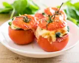 Trois tomates farcies au fromage fondant et aux herbes, servies sur une assiette blanche.