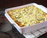 Un gratin de courgettes à l'ancienne, doré et crémeux, garni de rondelles de courgettes et de poireaux, prêt à être dégusté.