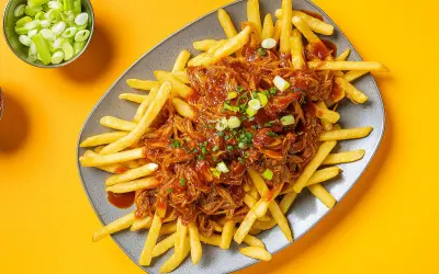 Frites croustillantes nappées d'une généreuse portion de pulled pork sauce barbecue, garnies de ciboule fraîche. Un délice !