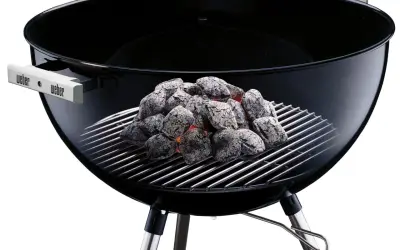 Grille foyère barbecue Weber avec charbon ardent. Elle sert à cuire vos aliments à la perfection.