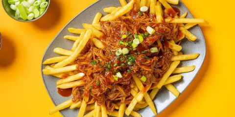 Frites croustillantes nappées d'une généreuse portion de pulled pork sauce barbecue, garnies de ciboule fraîche. Un délice !