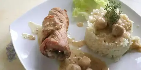 Délicieuse roulade de porc en sauce crémeuse, accompagnée d'une timbale de riz et d'une feuille de laitue.